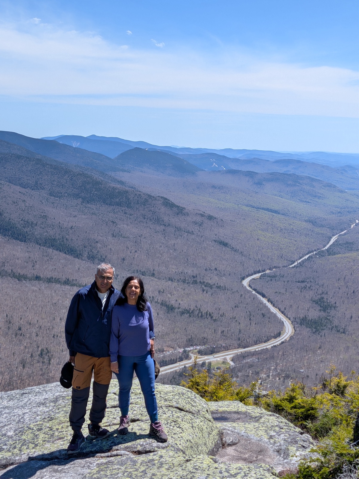 Two hikers on a granite ledge above a valley