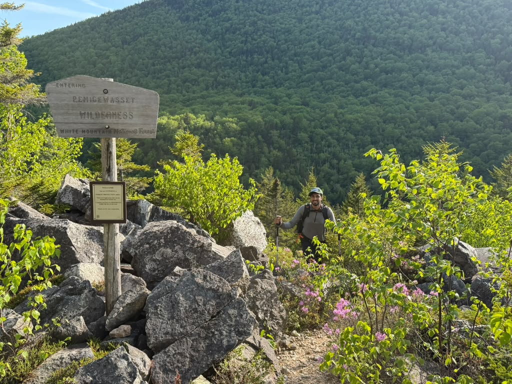Wooden wilderness boundary sign at a trail junction among boulders