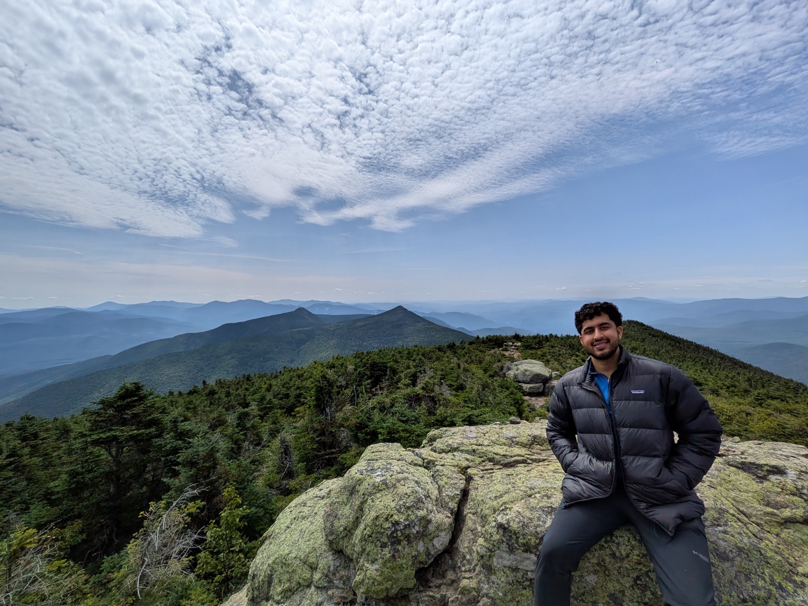 Hiker on summit rocks under a mackerel sky