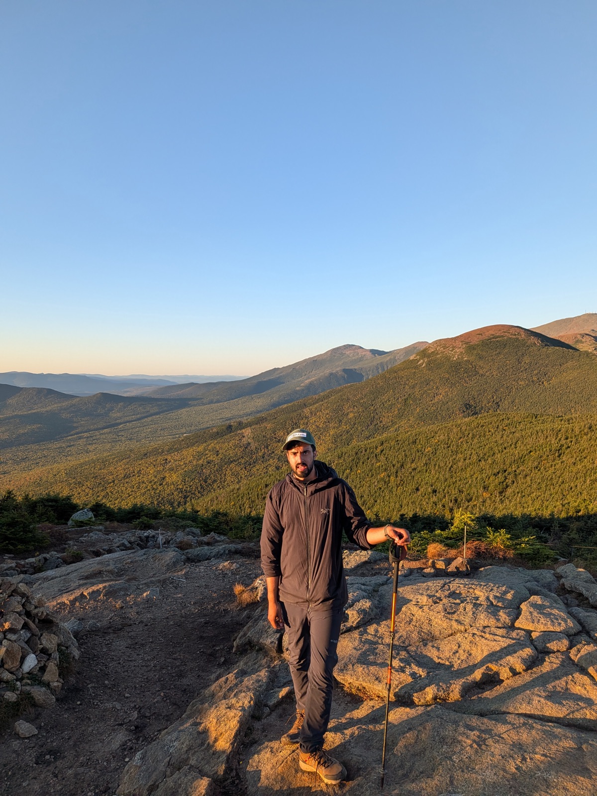 Hiker resting on open rock with mountains behind