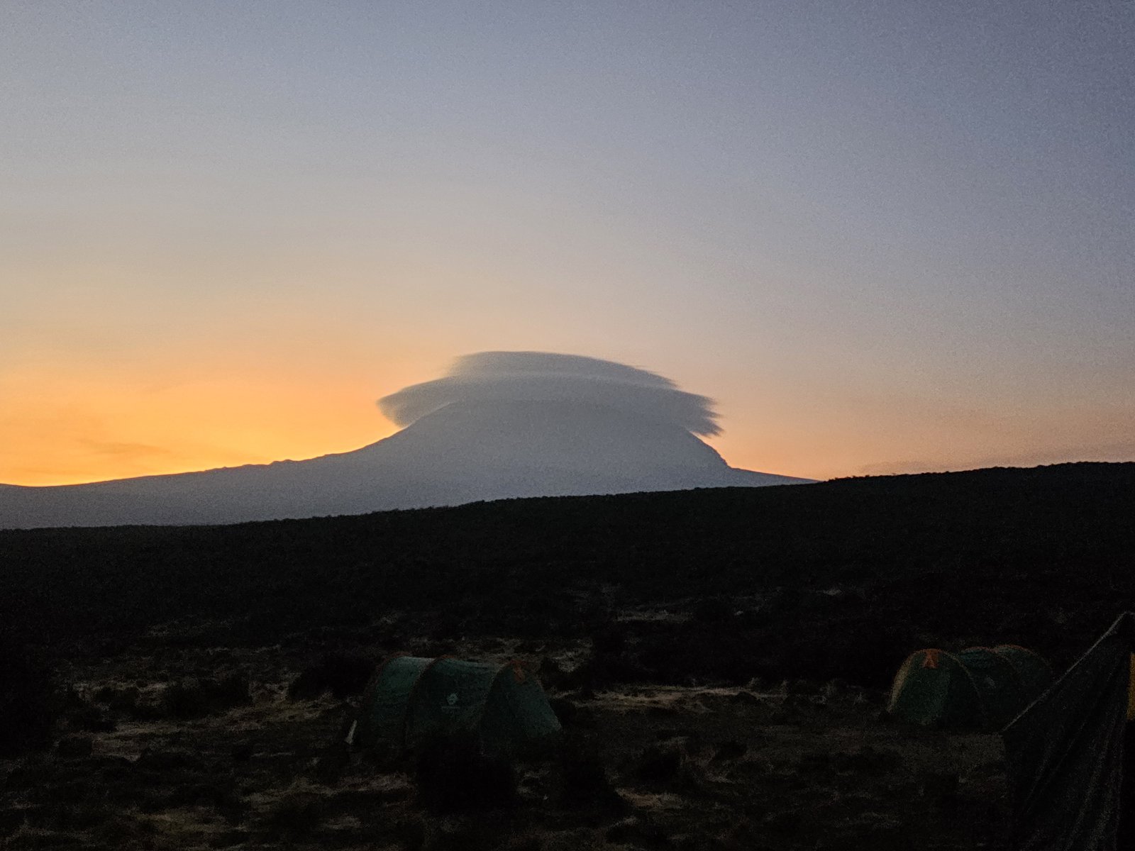 Kilimanjaro at dawn with a lenticular cloud capping the summit, tents in the foreground