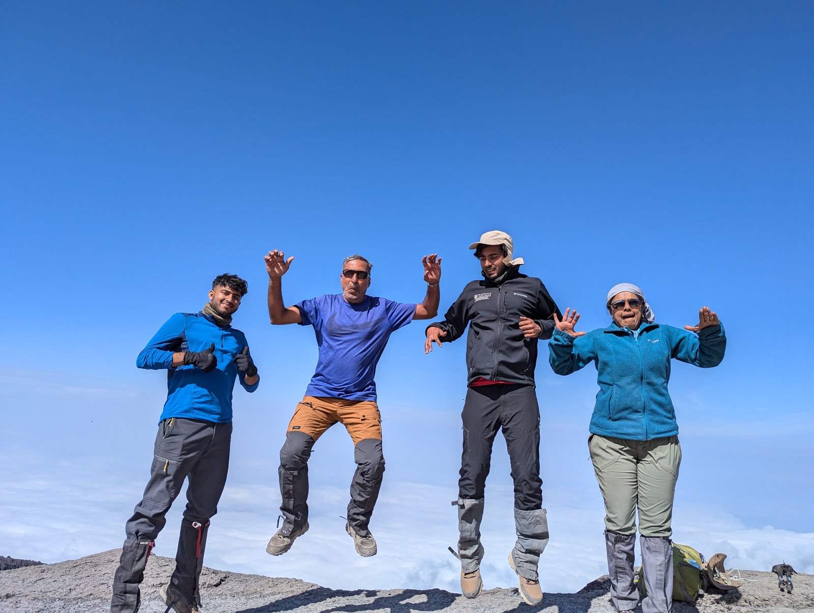 Four hikers jumping above a sea of clouds